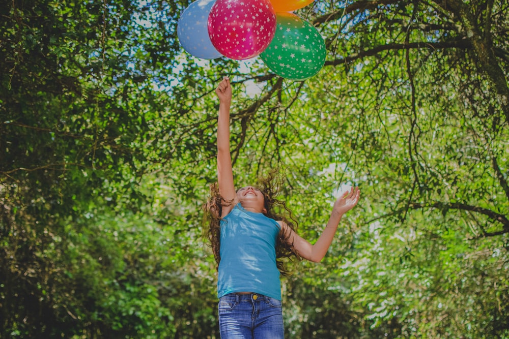 Mädchen spielt Luftballons unter Baum