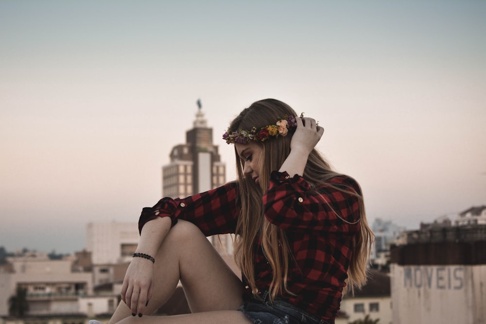 woman in red and black checked sport shirt with white high rise building backgorund