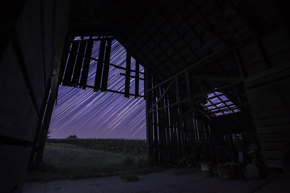 Langzeitbelichtung der Sterne über braunem Holzhaus während der Nacht