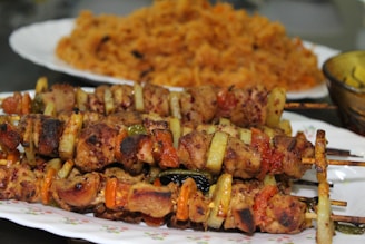 Close-up of a sizzling souvlaki skewer with pita and salad on the side.