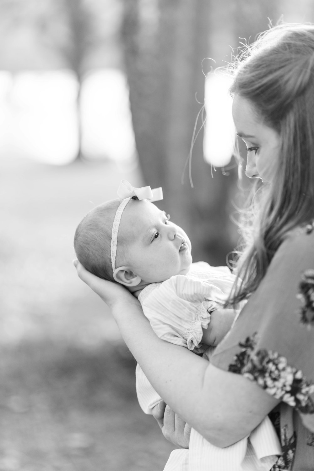 Foto de enfoque selectivo en escala de grises de mujer que lleva a un bebé