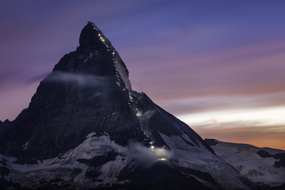 montanha coberta de neve sob o céu laranja e azul durante o dia