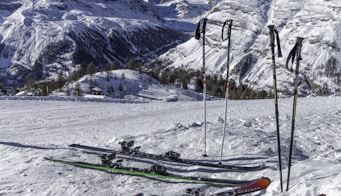 two pairs of red and green skis near mountain covered by snow at daytime