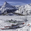 two pairs of red and green skis near mountain covered by snow at daytime