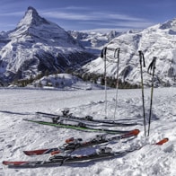 two pairs of red and green skis near mountain covered by snow at daytime