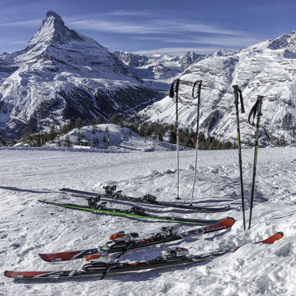 zwei Paar rote und grüne Skier in der Nähe des Berges, der tagsüber mit Schnee bedeckt ist