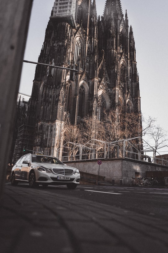 gray car on asphalt road near castle during daytime in Cologne Cathedral Germany