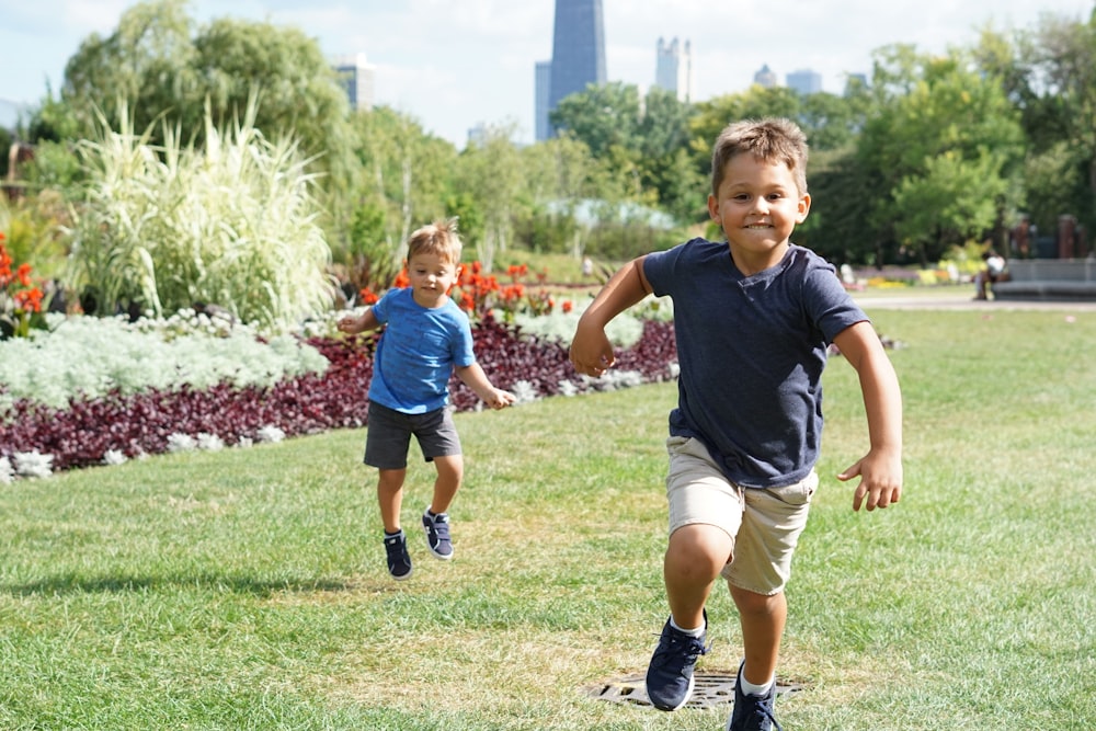 two boys walking on grasses during daytime