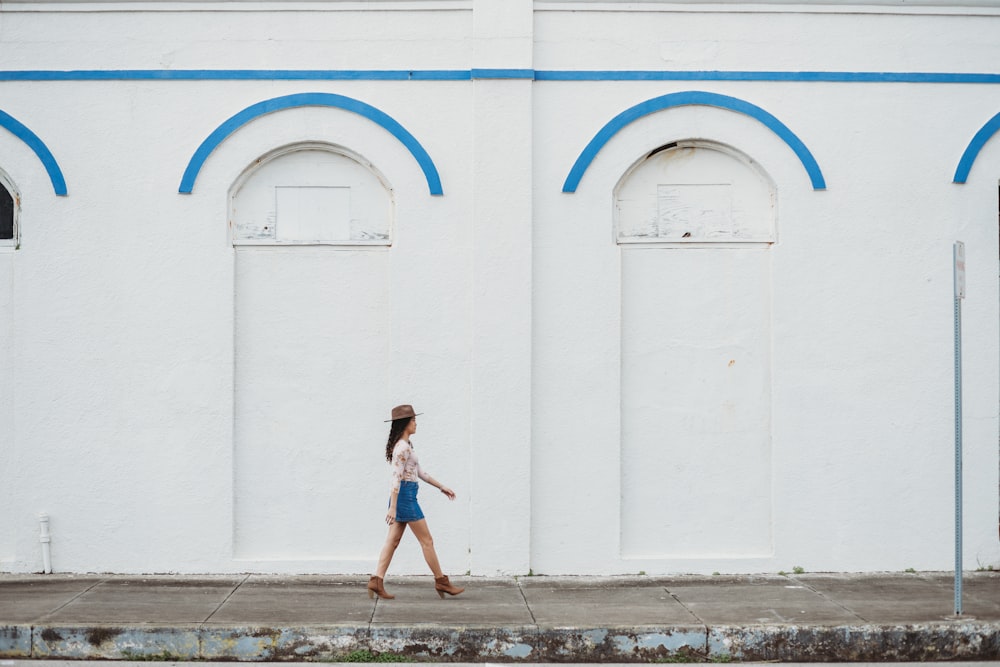 낮에 흰 콘크리트 건물 근처를 걷는 여자
