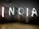 Individuals stand against a dimly lit background, creatively spelling out the word 'INDIA' with bright light trails. The light painting effect clearly highlights each letter, set against the darkened room.