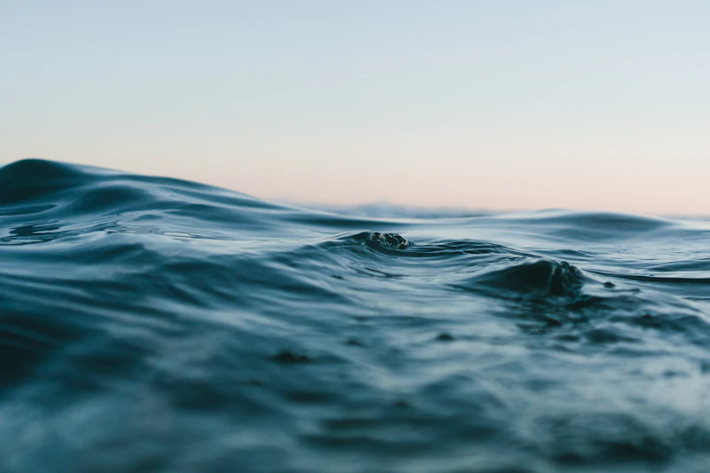 Abstract macro shot of clear water ripples with soft golden sunlight reflecting on the surface