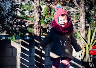 Smiling child wearing a cozy, stylish kids' outfit in a sunny park.