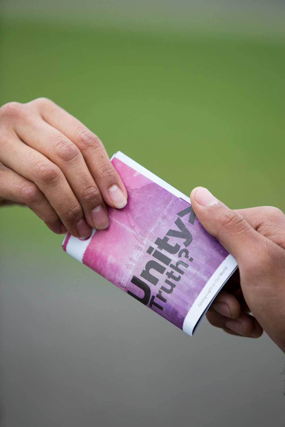 Hands passing a colourful pamphlet to another person