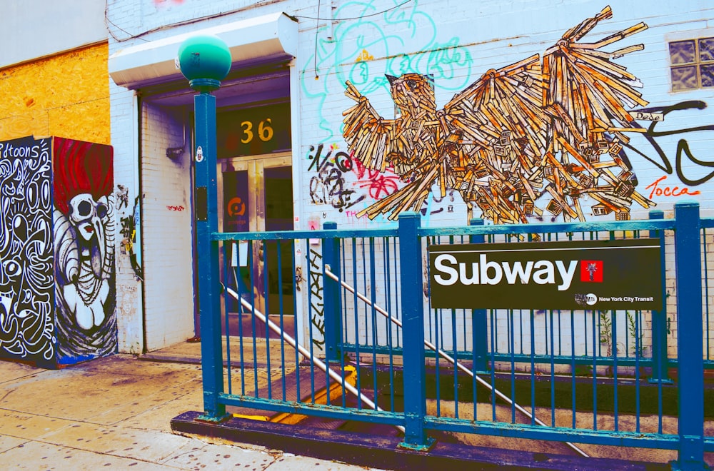 trilho de metal azul com sinalização do metrô perto do prédio com arte de grafite