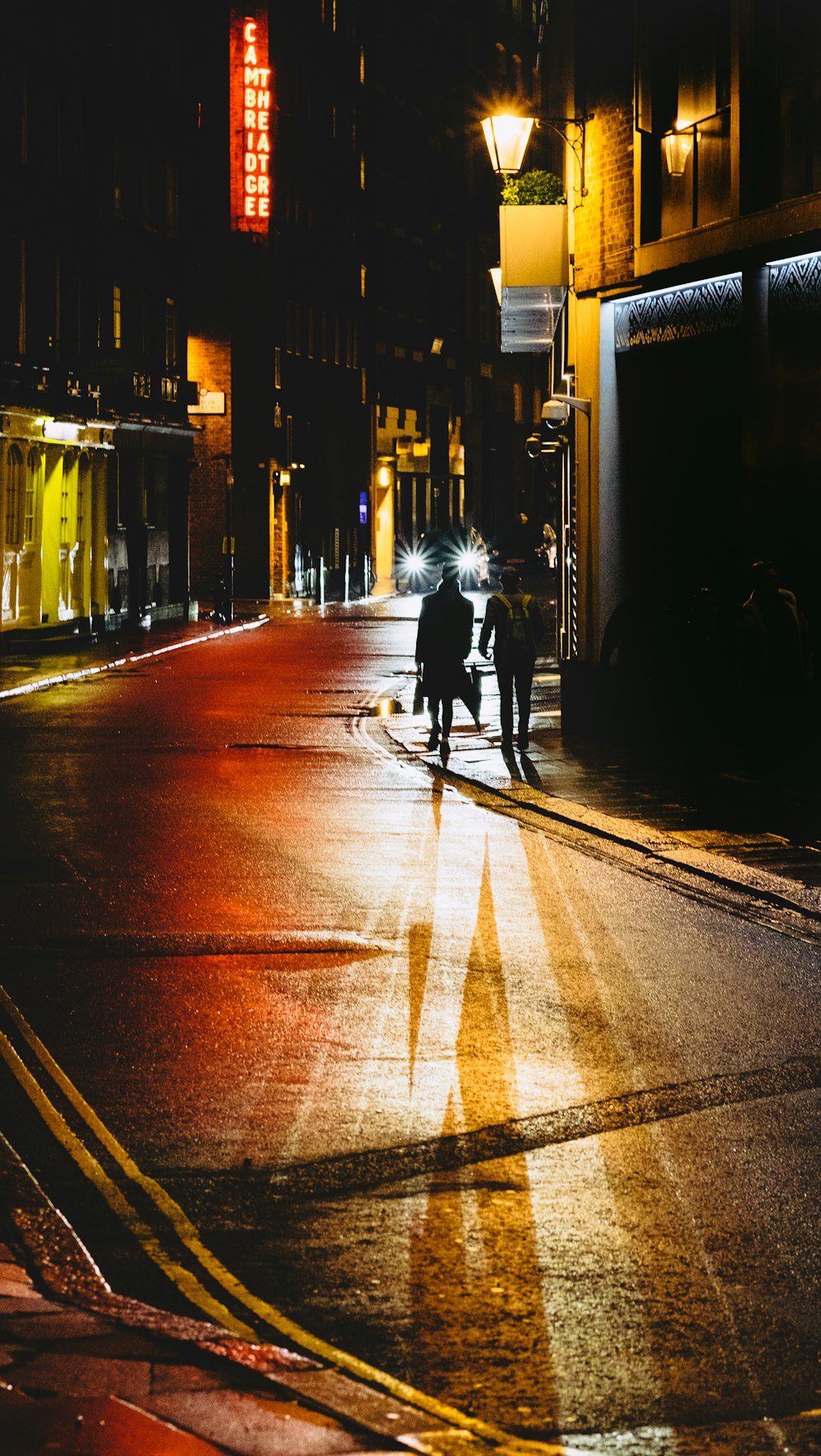 zwei Personen, die nachts auf der Straße neben dem Gebäude spazieren gehen