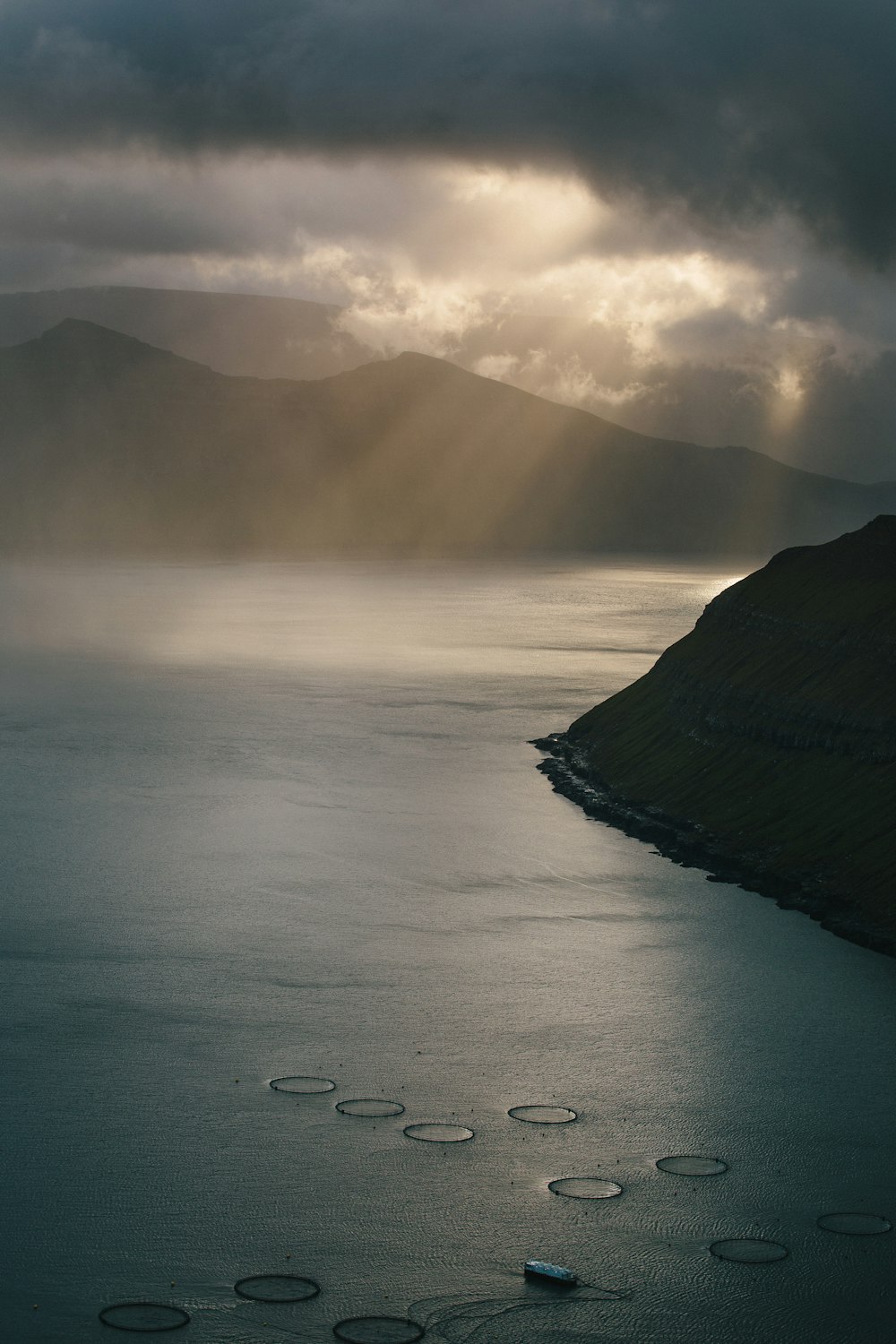 mountain near body of water under cloudy sky