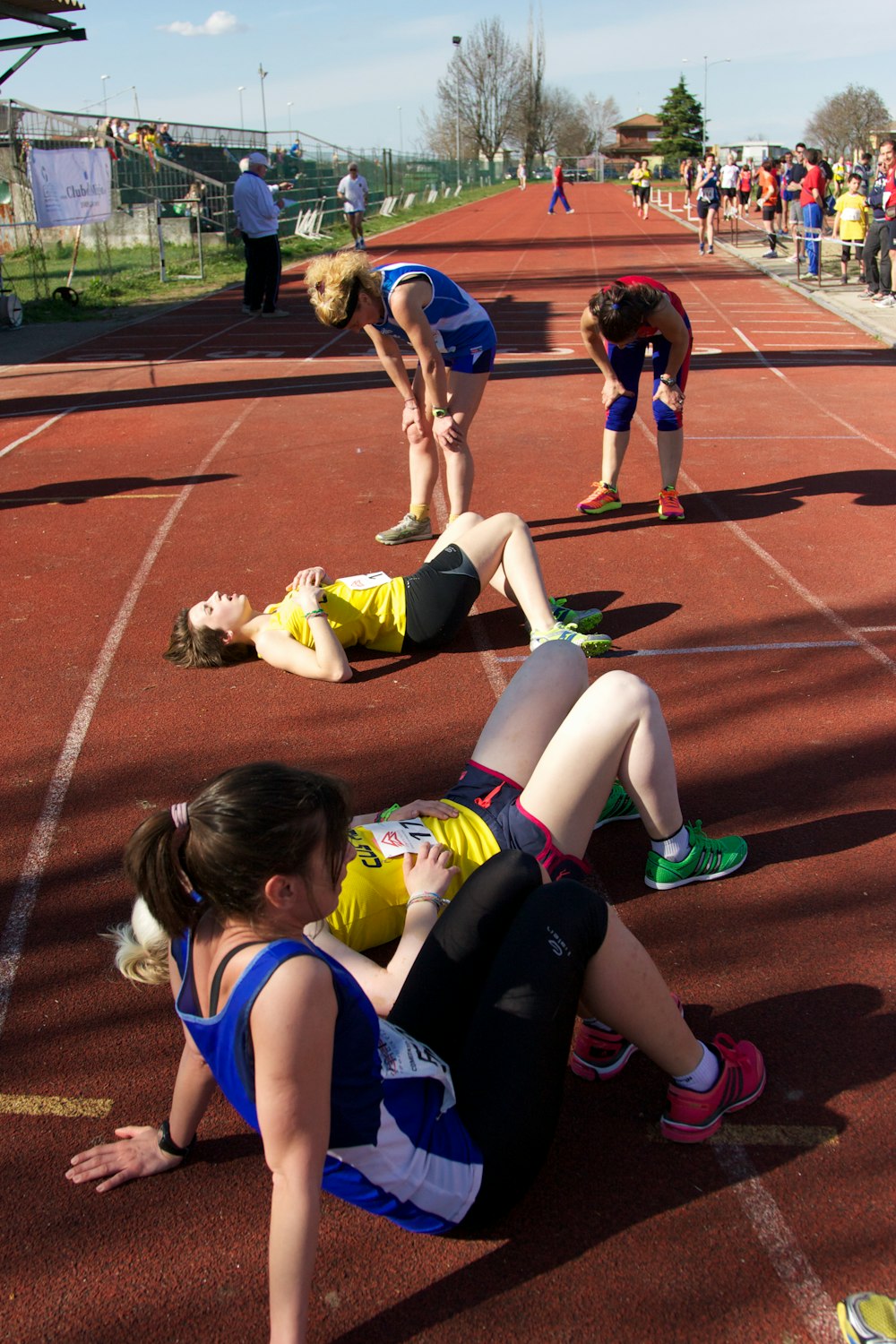 Cinq femmes debout sur une piste d’athlétisme brune