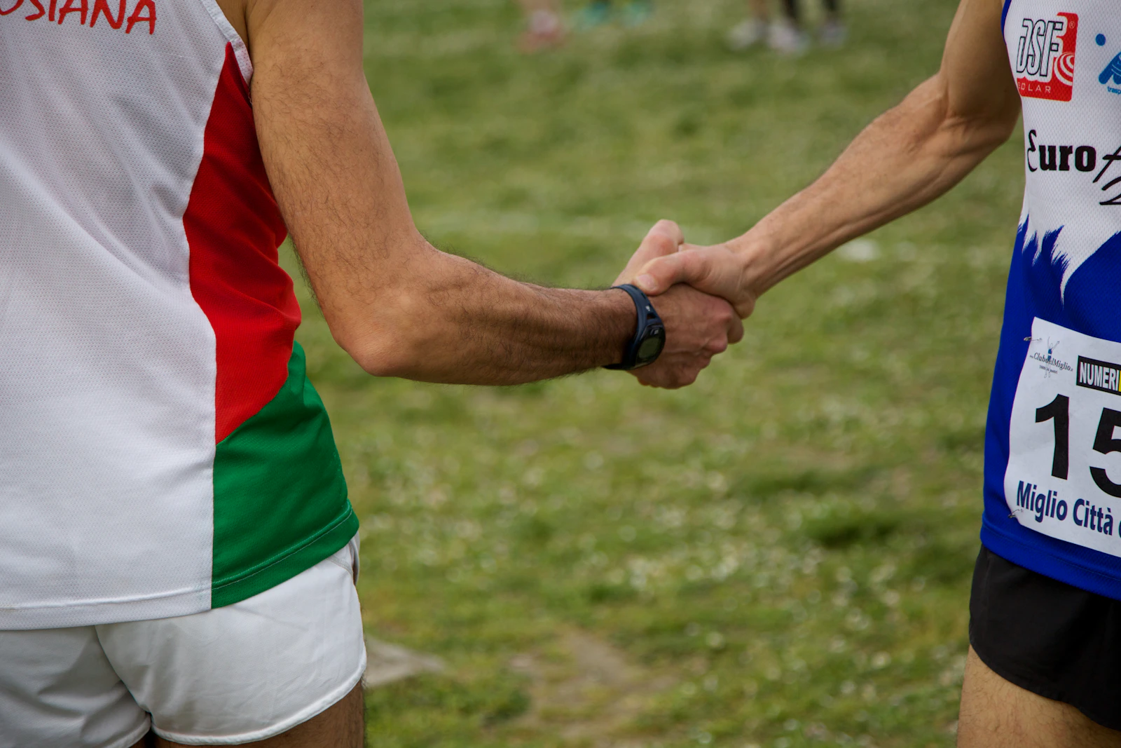 A relay runner's hand passing a baton to the next runner