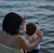 woman holding girl near body of water