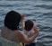 woman holding girl near body of water