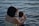 woman holding girl near body of water
