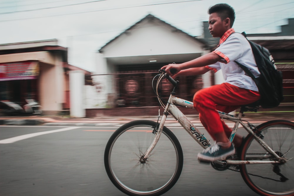 timelapse photo of boy riding bicycle in middle of roadway