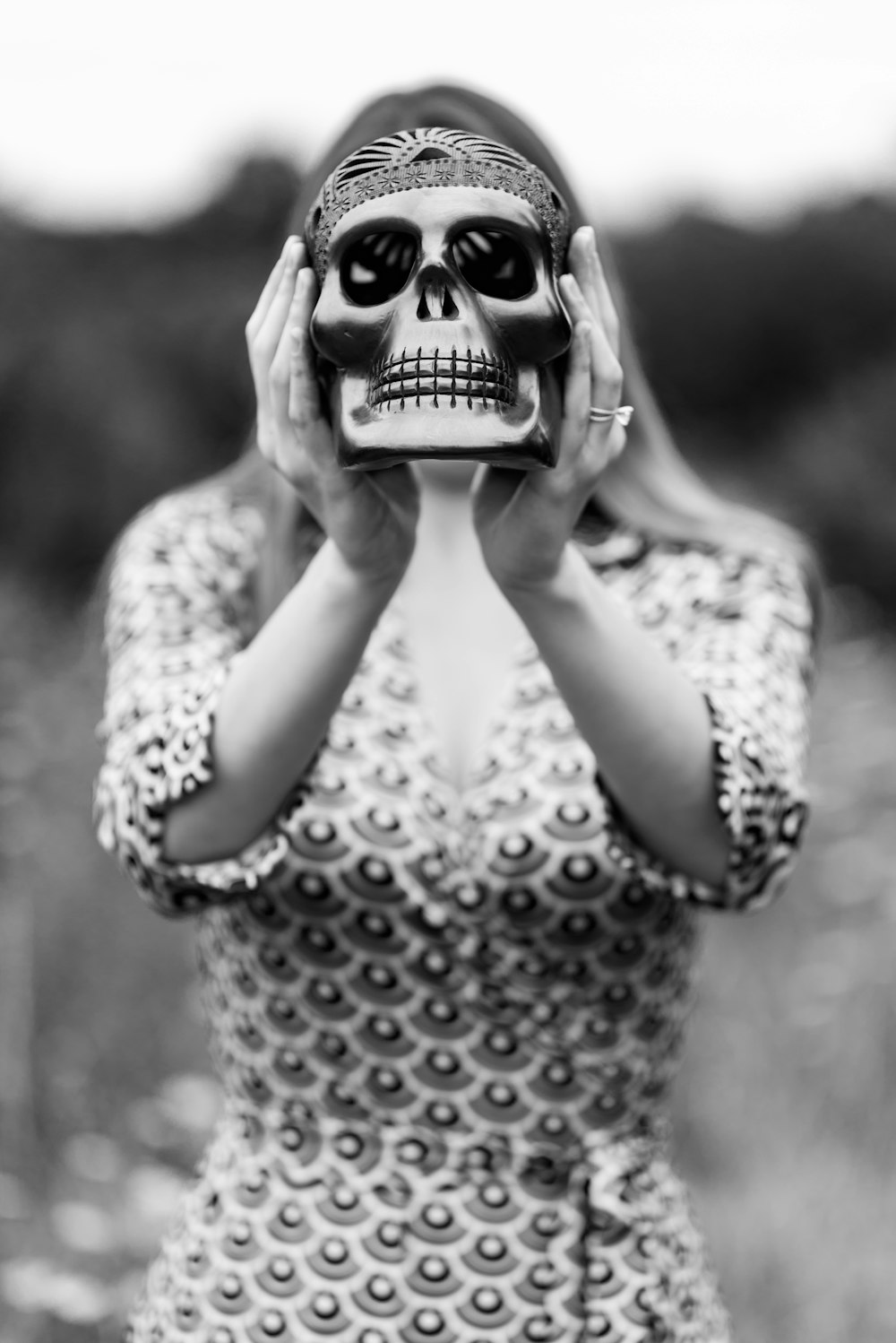 Photographie en niveaux de gris d’une femme tenant une figurine de crâne