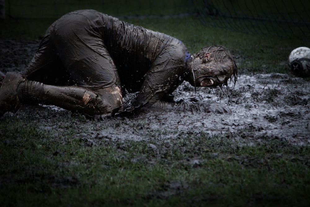 泥にまみれた緑の芝生に横たわる男