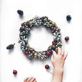 person making bauble and pinecone wreath