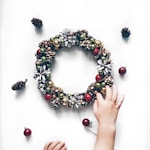 person making bauble and pinecone wreath