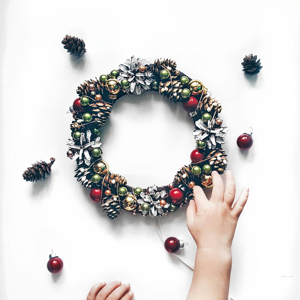person making bauble and pinecone wreath