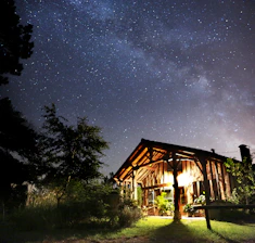 Soft glowing outdoor lights illuminating a rustic cabin surrounded by wilderness