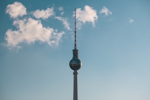 A team of technicians carefully assembling a tall telecom tower against a clear blue sky