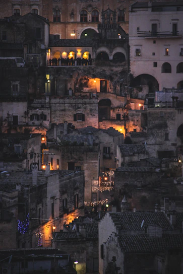 A vibrant evening shot of Alcalá de Henares cityscape with warm golden lights reflecting on historic buildings.