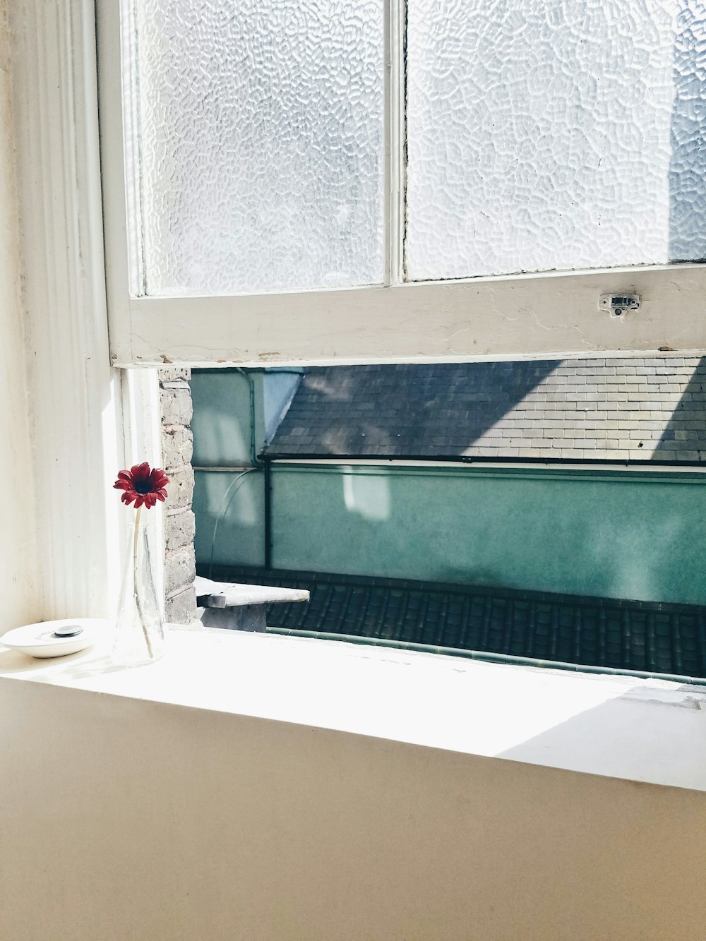 a vase with a flower sitting on a window sill