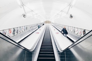 people riding escalator inside white room