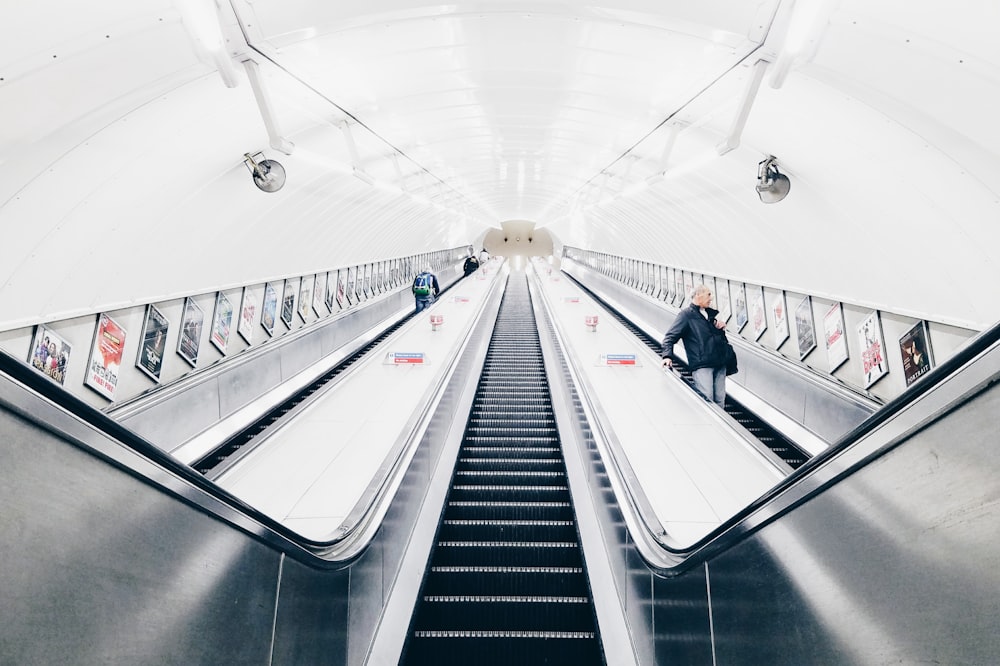 people riding escalator inside white room