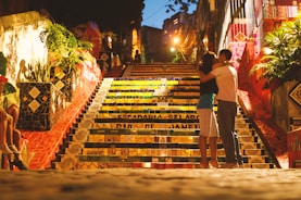 man and woman kissing in front of stairs