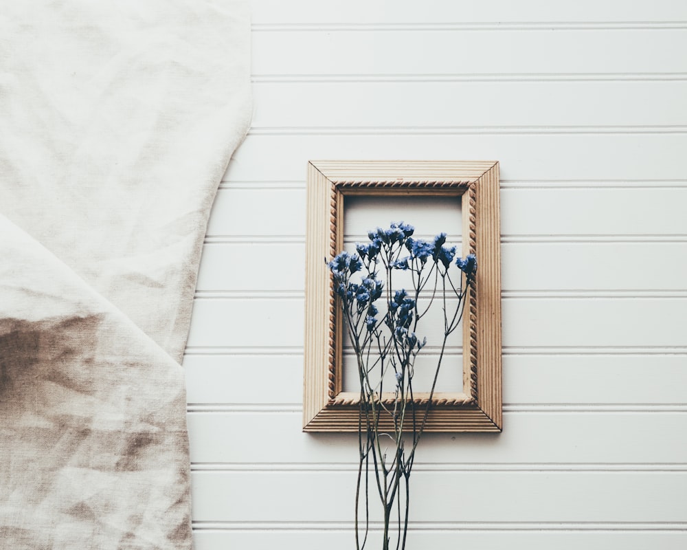 blue petaled flowers in front on brown wooden frame
