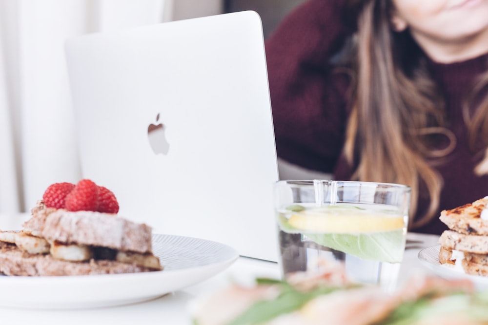 klares Trinkglas in der Nähe des silbernen MacBooks