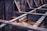 Rusted steel beams form a grid-like structure with visible signs of weathering and oxidation. The metal surfaces are covered with patches of rust, creating a textured appearance. The beams intersect at right angles, creating a sense of industrial design and architecture.