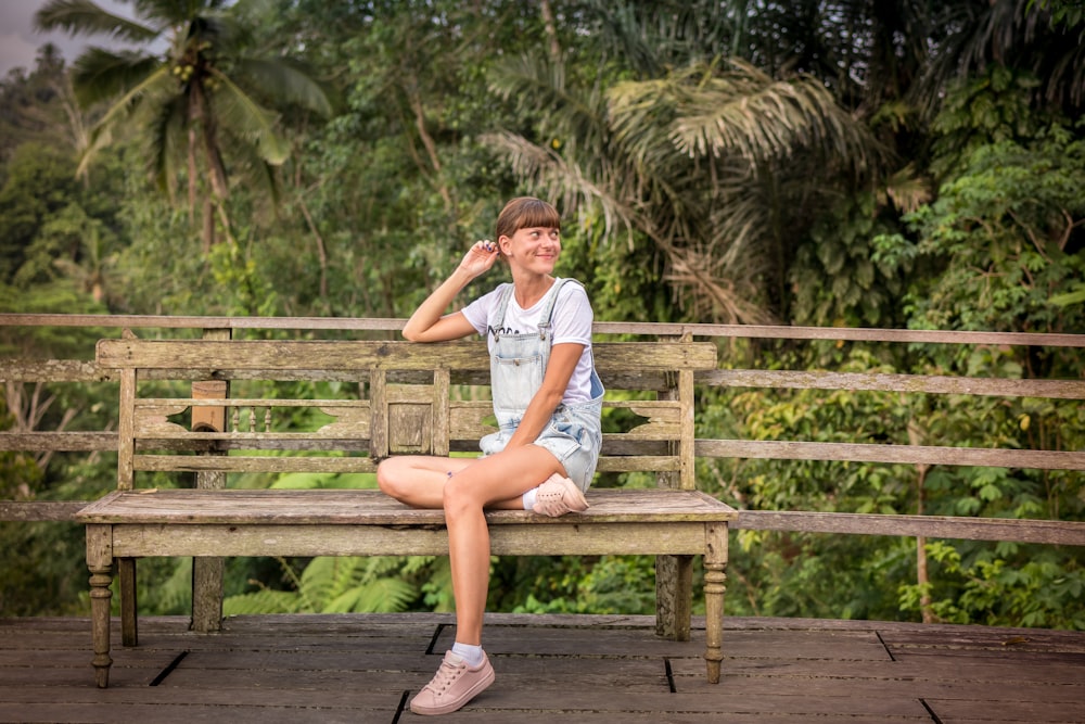 smiling woman sitting on bench near trees during daytime