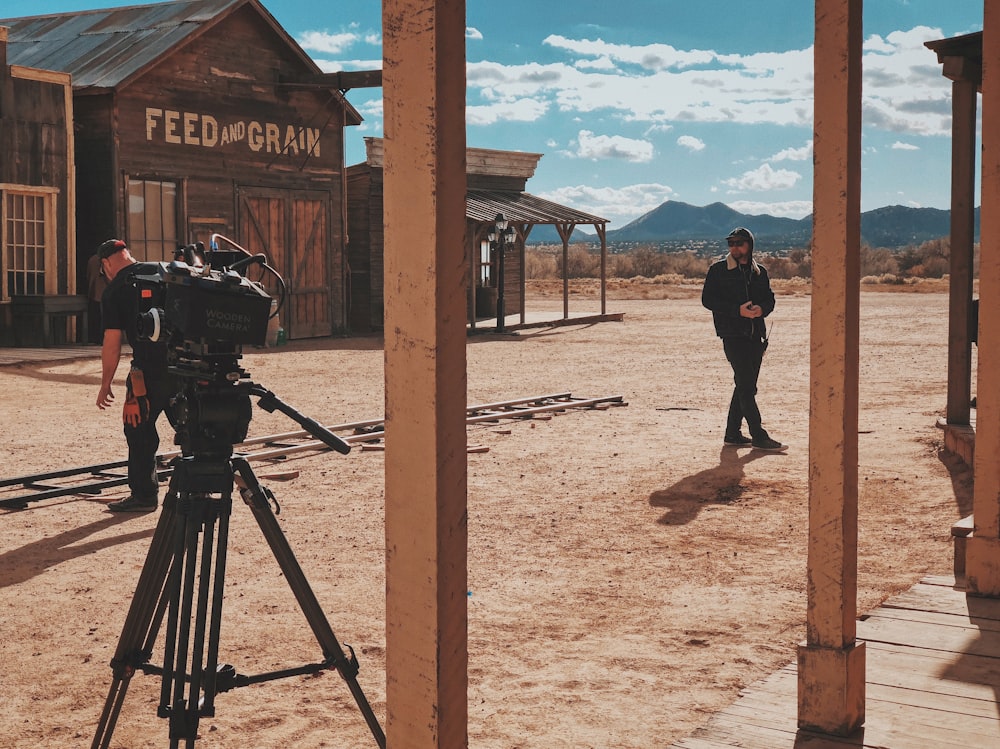 homem na jaqueta preta e calças em pé na frente da câmera de vídeo profissional de gravação