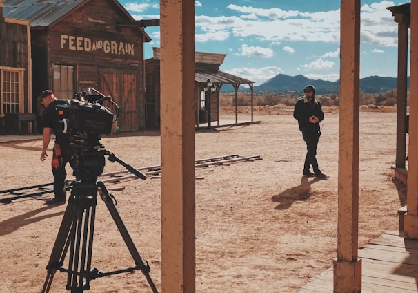 man in black jacket and pants standing in front of recording professional video camera