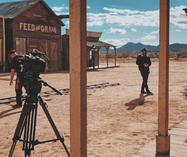 man in black jacket and pants standing in front of recording professional video camera