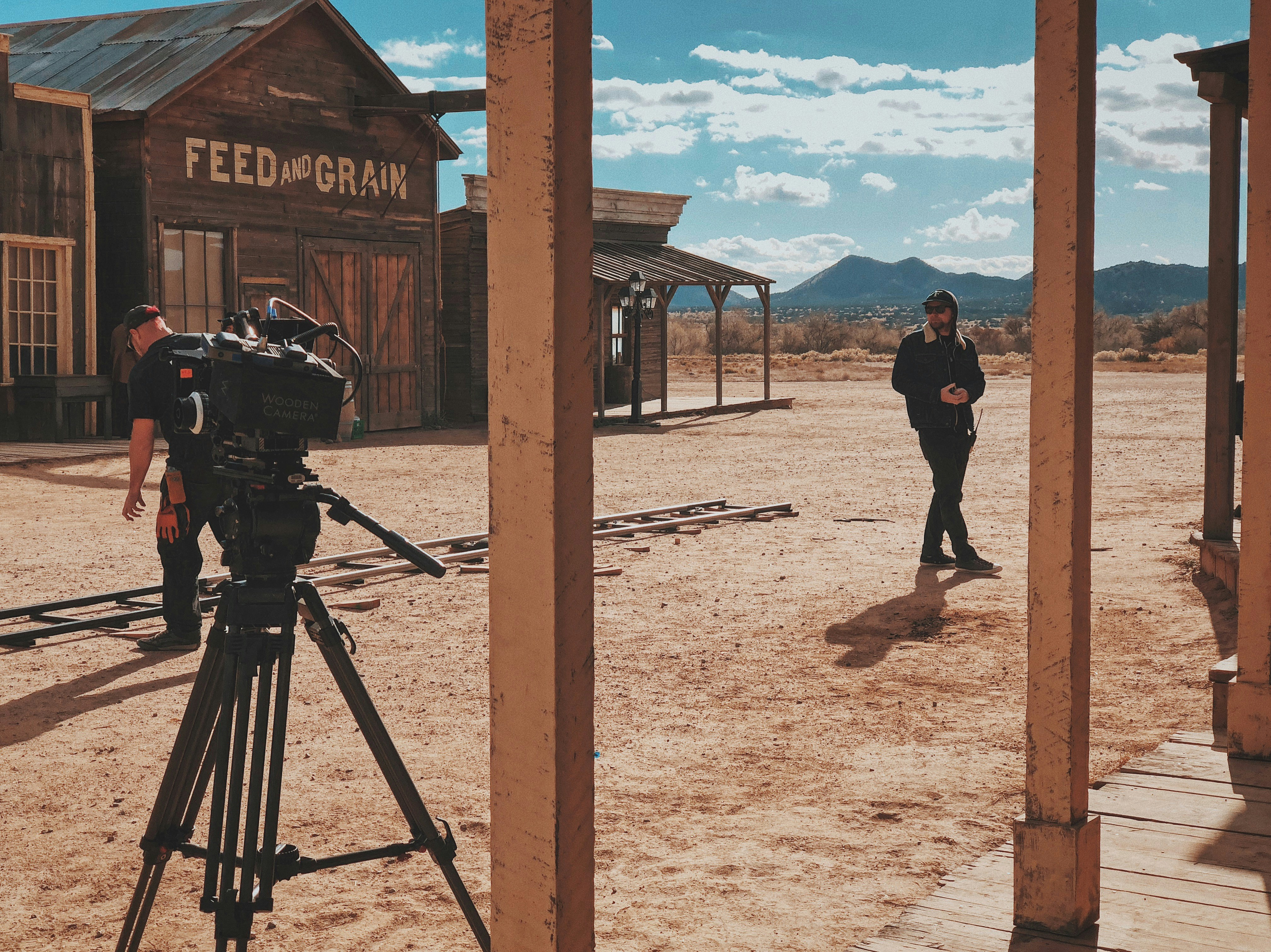 man in black jacket and pants standing in front of recording professional video camera