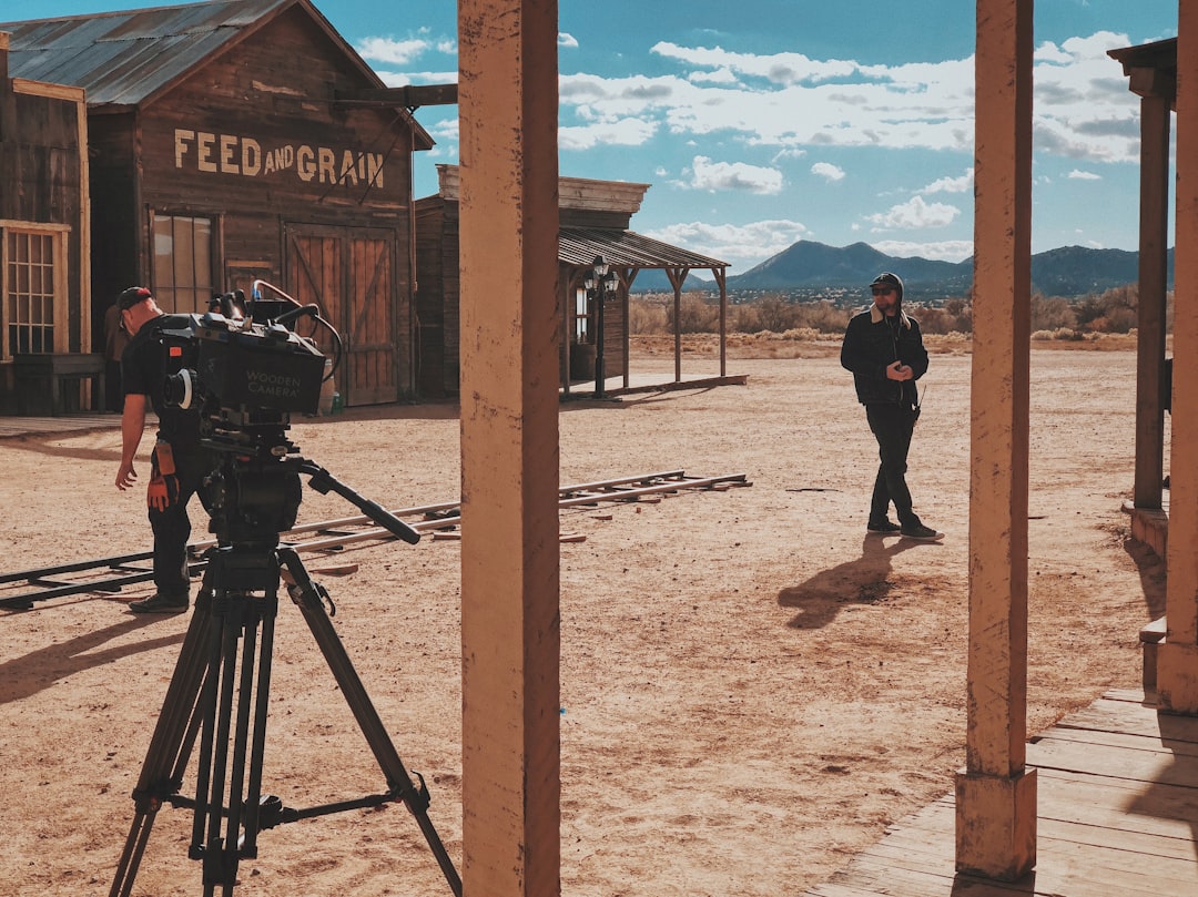 man in black jacket and pants standing in front of recording professional video camera,