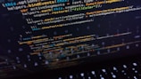 Lines of code displayed on a computer screen, featuring syntax used in programming languages such as JavaScript. The screen shows various functions and variables highlighted in different colors, hinting at coding activity.