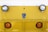 A close-up view of the front of a yellow industrial vehicle with two round headlights and two orange reflectors. The surface features a diamond plate pattern and a logo that reads 'Taylor Dunn' in the center.