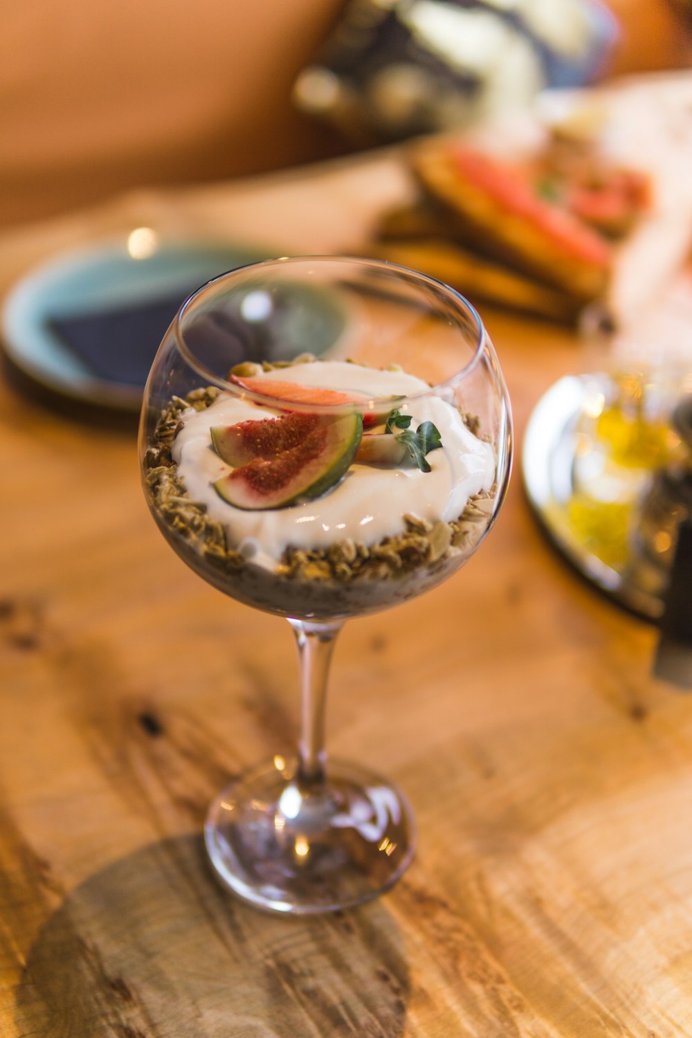 Fruits tranchés et crème dans un verre à vin transparent à longue tige